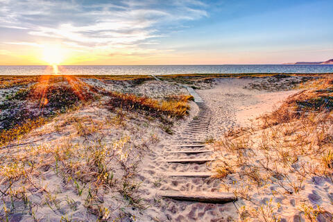 Trail leading through dunes to Lake Michigan at sunset in Sleeping Bear Dunes National Lakeshore.