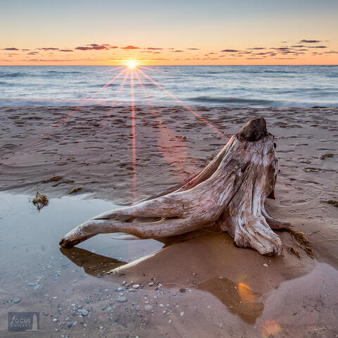 Driftwood log on the Lake Michigan beach at sunset.
