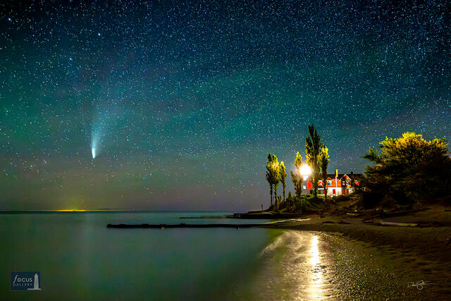 Comet NEOWISE in a starry sky over Lake Michigan at Point Betsie Lighthouse, Michigan.