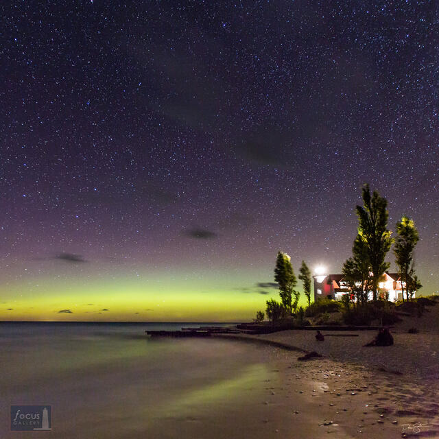 Glow of aurora borealis over Point Betsie Lighthouse and Lake Michigan.