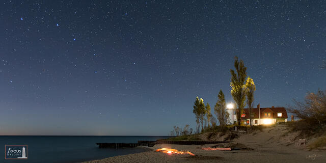 Starry sky and Big Dipper over Point Betsie Lighthouse and a fire on the beach.