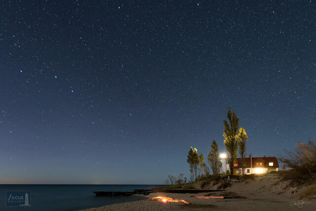 Starry sky and Big Dipper over Point Betsie Lighthouse and a fire on the beach.