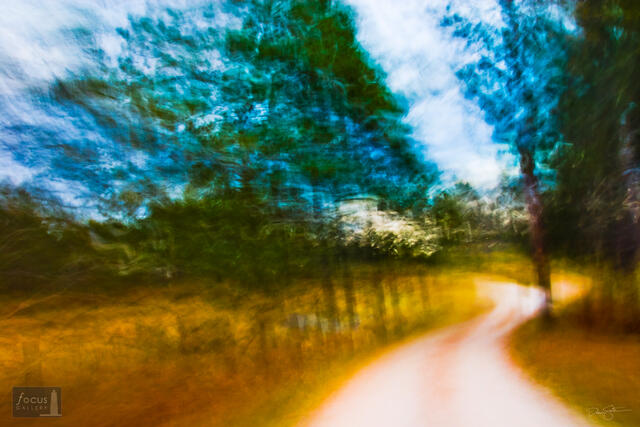 Impressionistic image of a curvy road through trees in the fall.