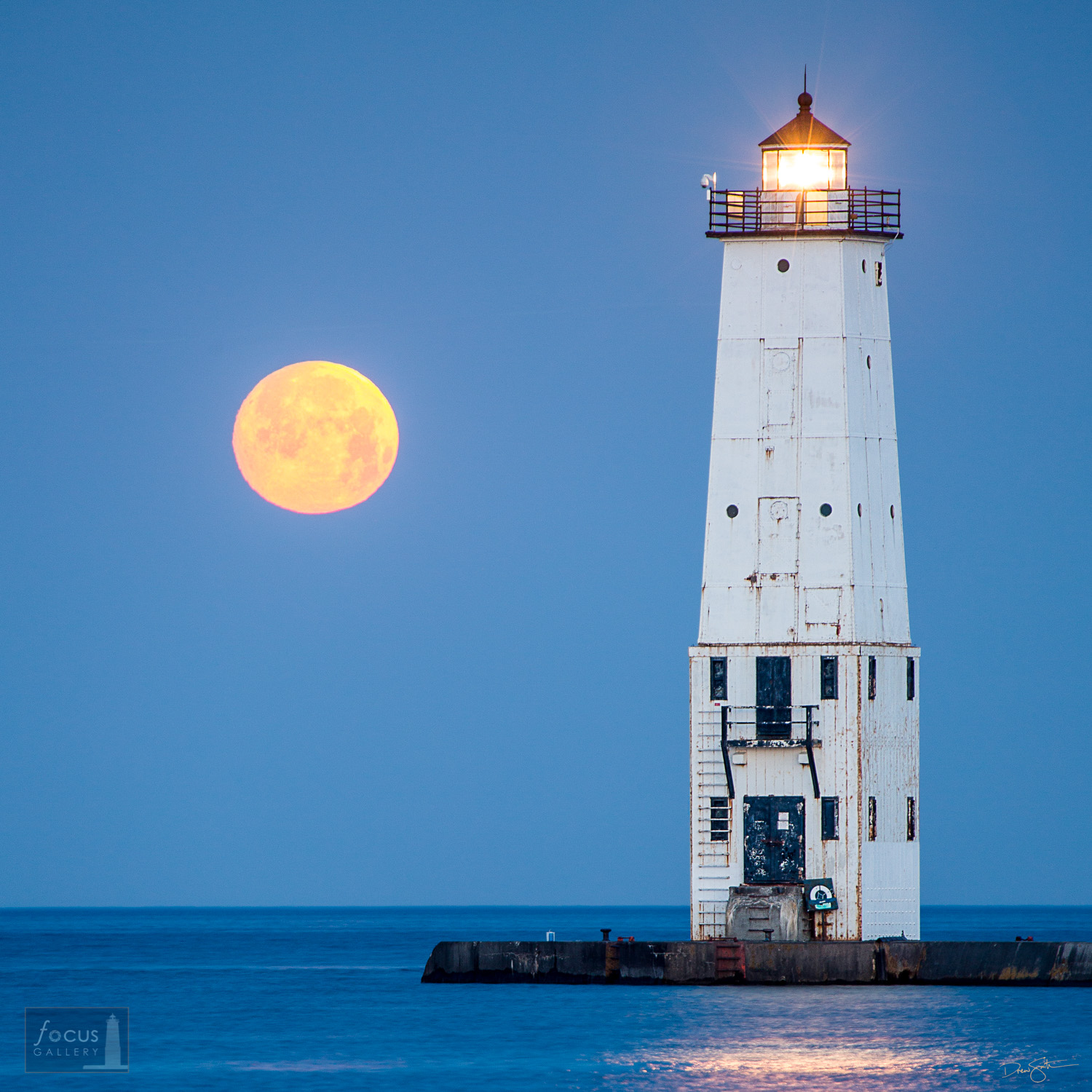 Full moon setting over Frankfort Lighthouse and Lake Michigan.