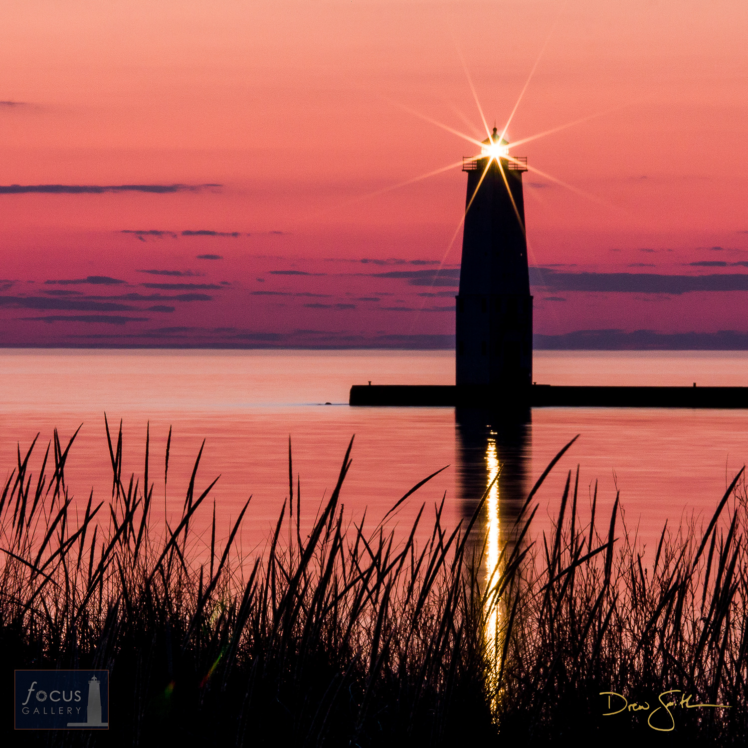 The last light of day and the beacon of the Frankfort North Breakwater Lighthouse are reflected on the calm waters of Lake Michigan...