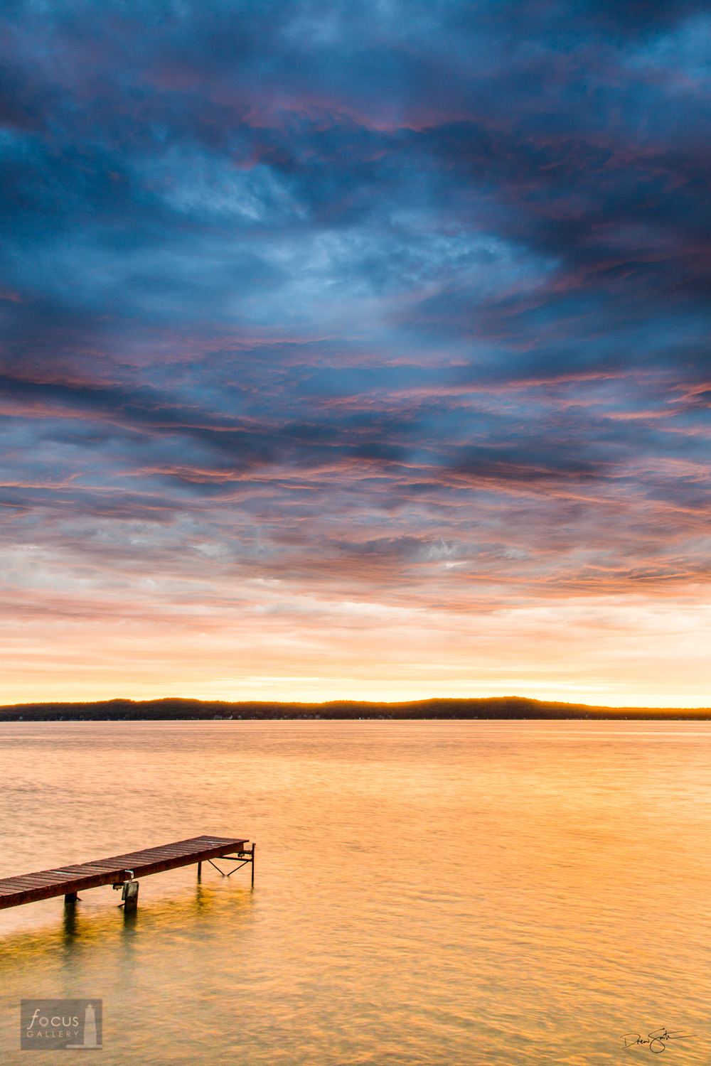Colorful sunrise over Platte Lake with a dock.