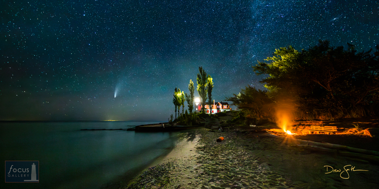 Night sky with Comet NEOWISE over Point Betsie Lighthouse and a beach fire.