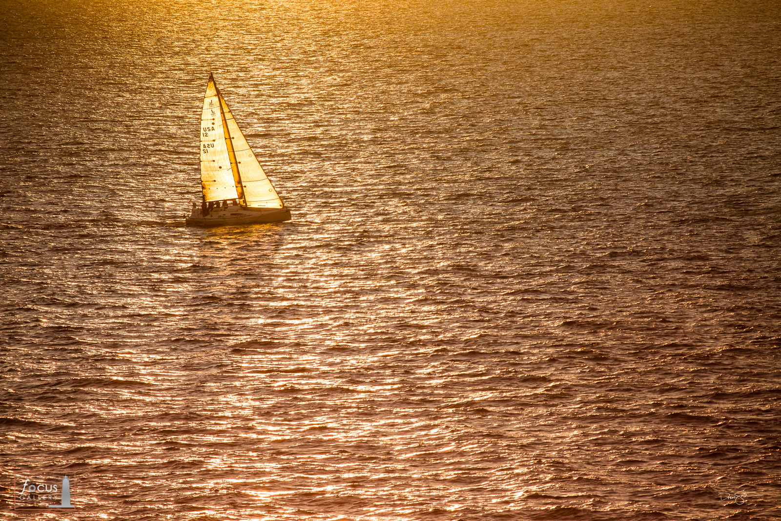 Backlit sailboat participating in the Chicago to Mackinac race on Lake Michigan at sunset.