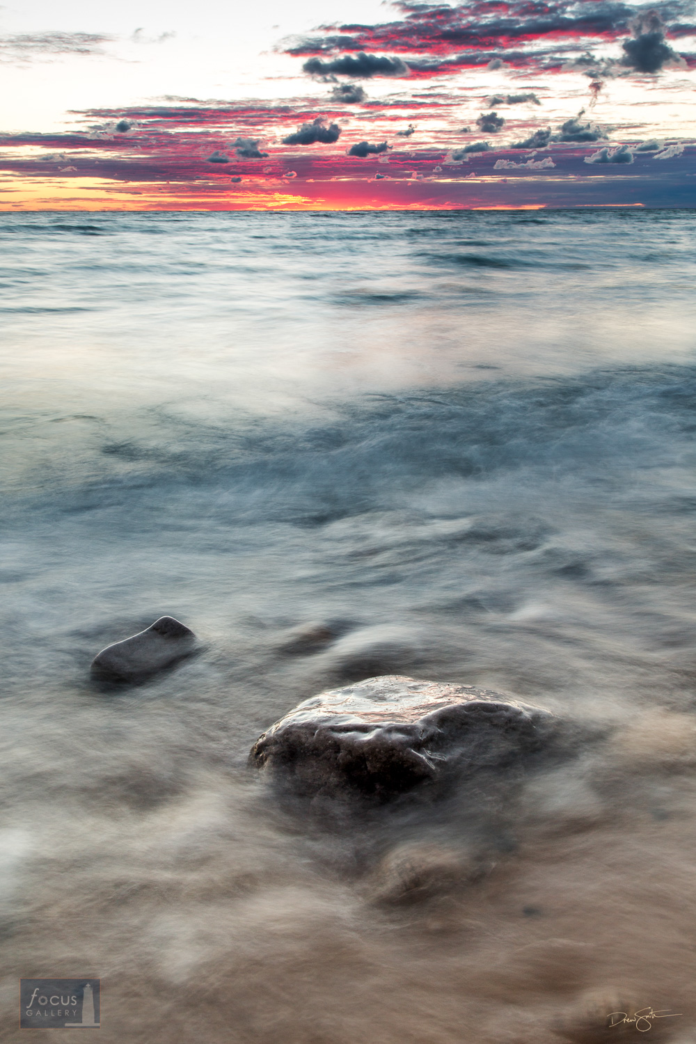 Lake Michigan waters and boulder at sunset.