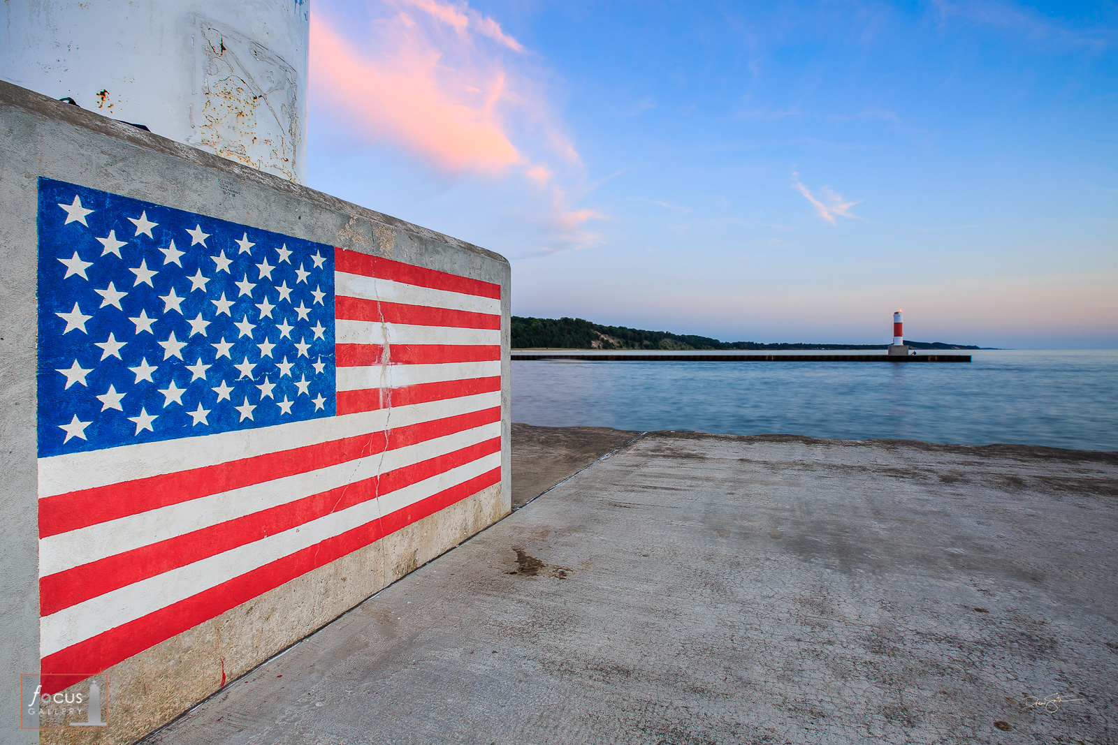 Painting of the American Flag on the base of the Portage Point Lighthouse in Onekama, Michigan at sunset.