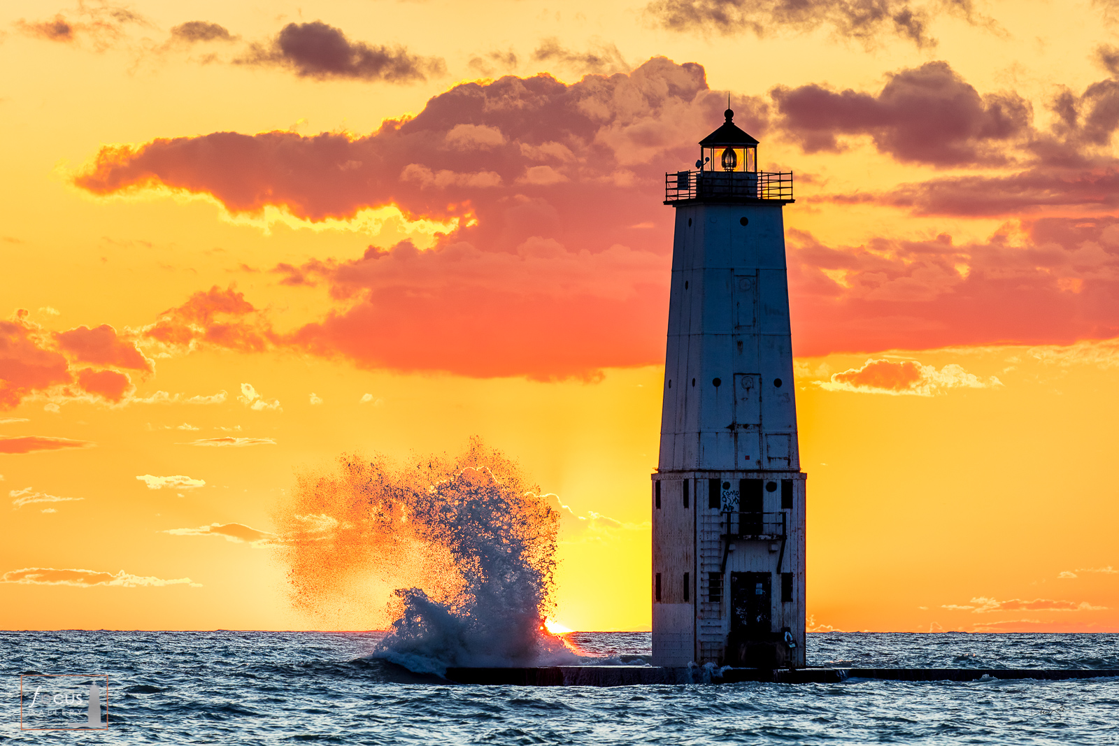 Waves crash at sunset with the Frankfort North Breakwater Lighthouse and colorful clouds.