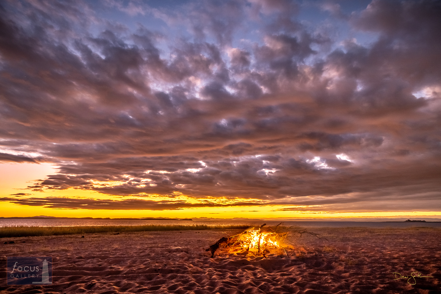 A bonfire burns and the colors of sunset glow in the sky along the shores of Lake Kariba.